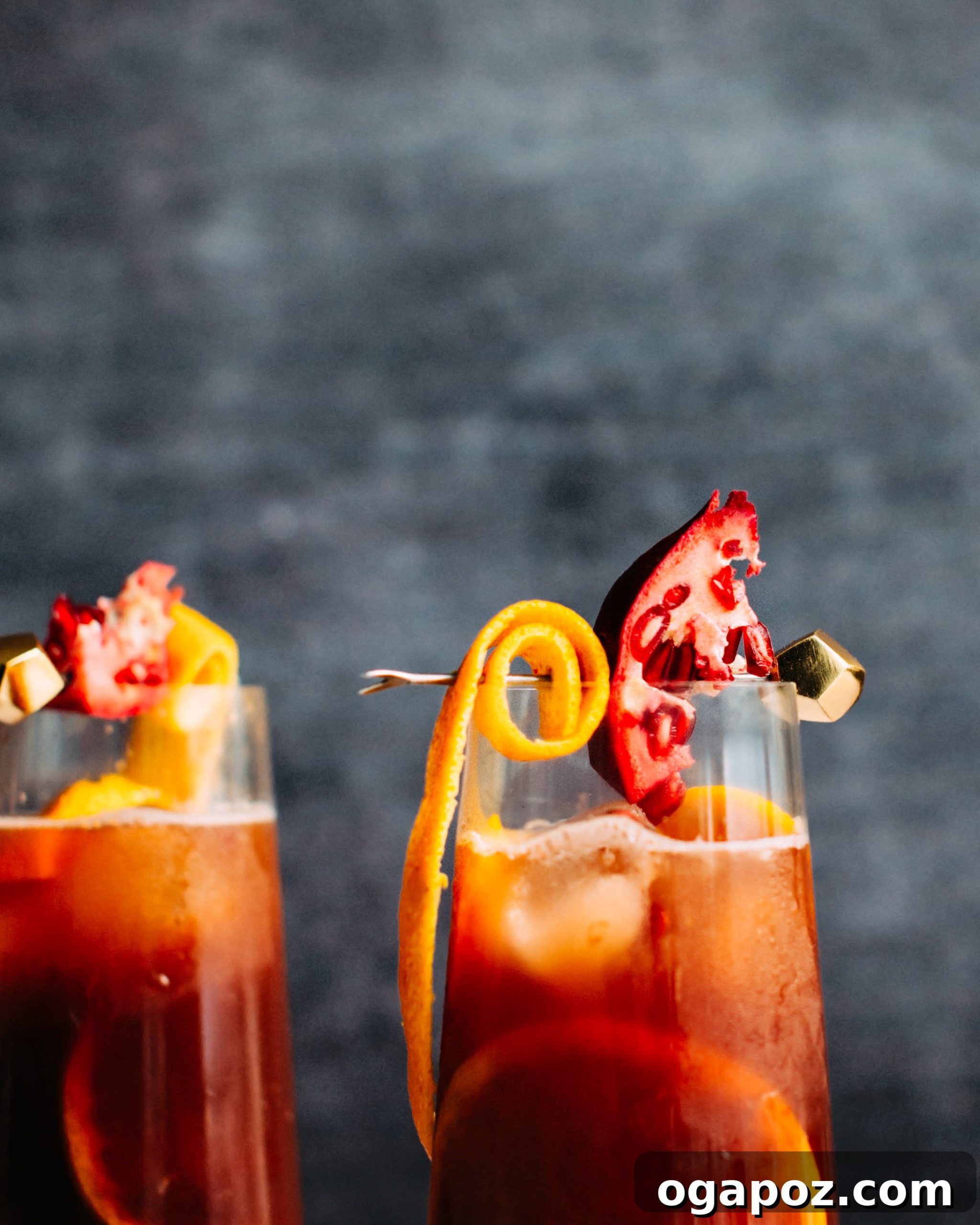 A single glass of Christmas Sangria garnished with an orange slice, pomegranate wedge, and orange peel.
