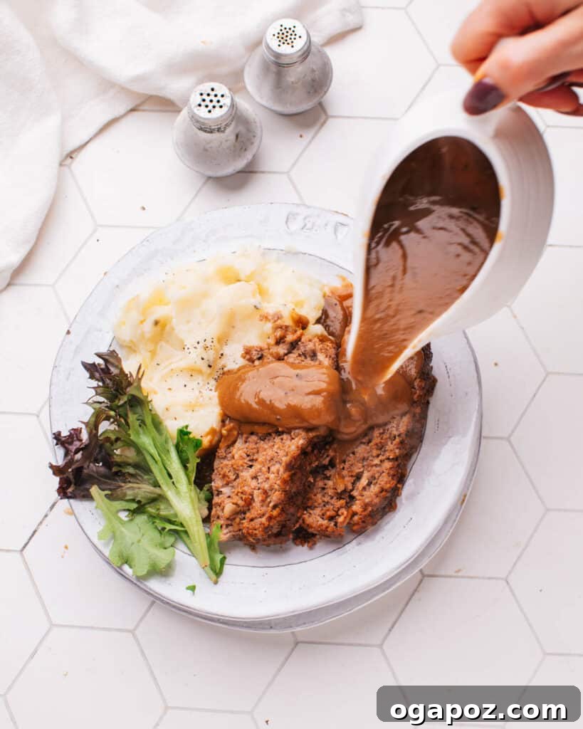 Tender Meatloaf, Velvety Brown Gravy 3 Meatloaf with Brown Gravy being poured over it.