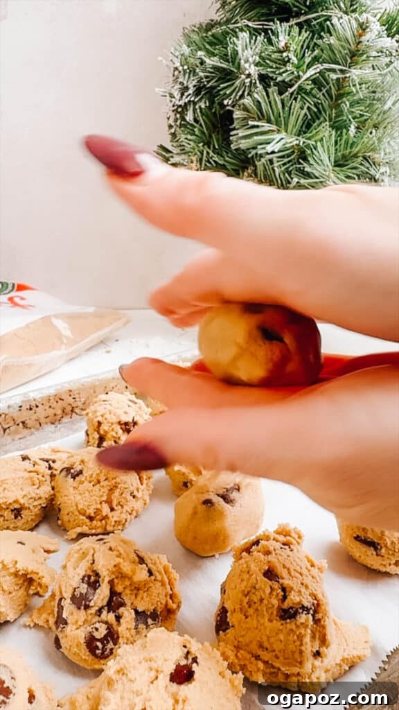 Effortless Cookie Dough Bites 11 Hands rolling cookie dough into smooth, uniform balls on a flat surface.