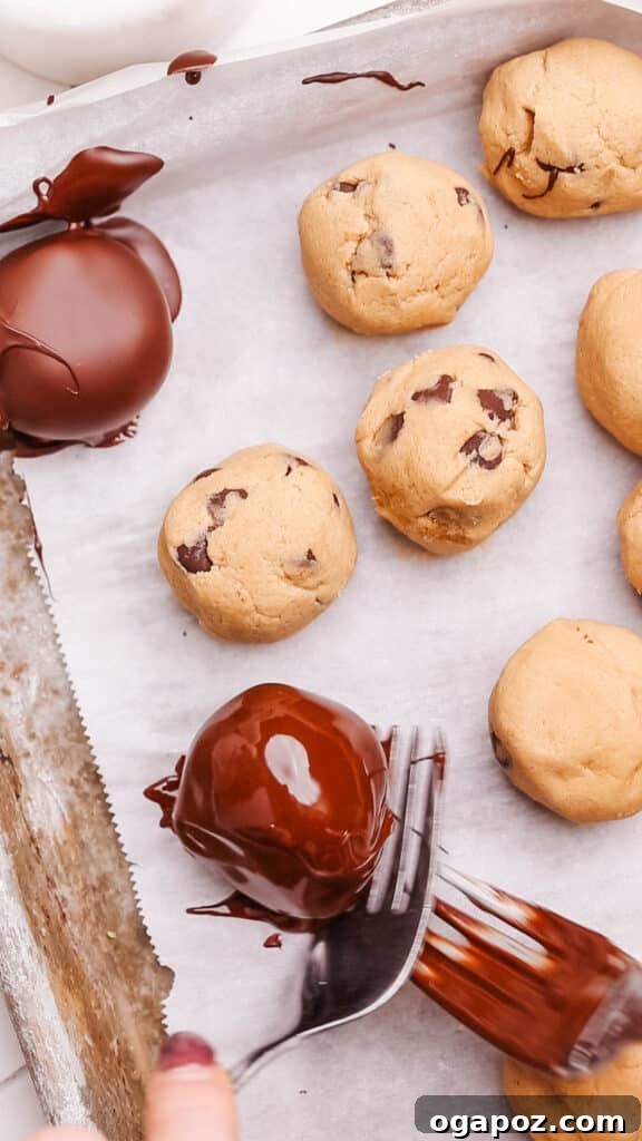 Effortless Cookie Dough Bites 15 Multiple chocolate-dipped cookie dough bites arranged neatly on a parchment-lined baking sheet, ready for setting.
