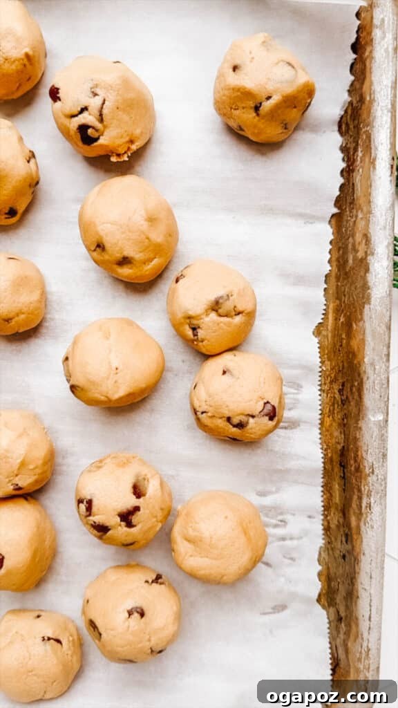 Effortless Cookie Dough Bites 6 Raw cookie dough balls perfectly arranged on a parchment-lined baking sheet, ready for chilling.