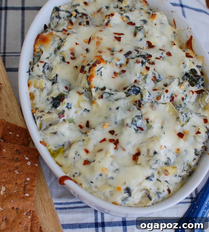 Zesty Lemon Artichoke Spinach Dip 4 A close-up of Lemon Spinach Artichoke Dip in a white ceramic bowl, showcasing its gooey texture