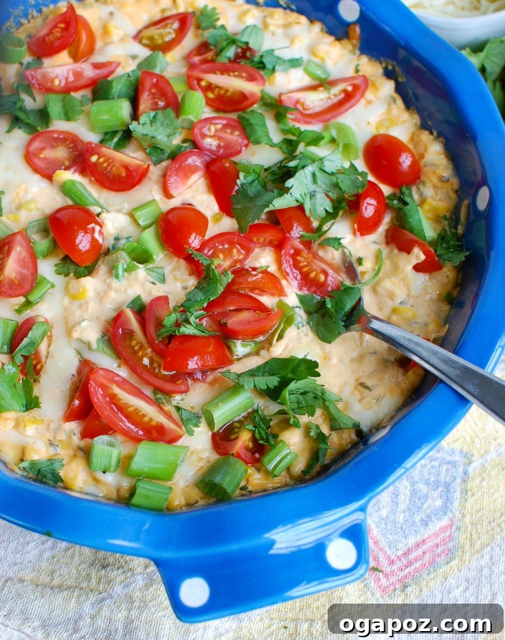 Close-up side view of Baked Sriracha Sweet Corn Dip with vibrant toppings, emphasizing its texture