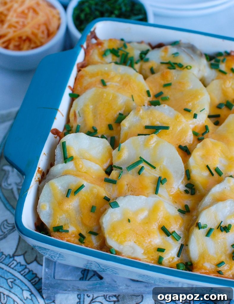 Creamy Spinach Artichoke Potato Gratin 5 Spinach Artichoke Scalloped Potatoes baked in a blue ceramic baking dish, bubbling hot and ready to be served from the oven.