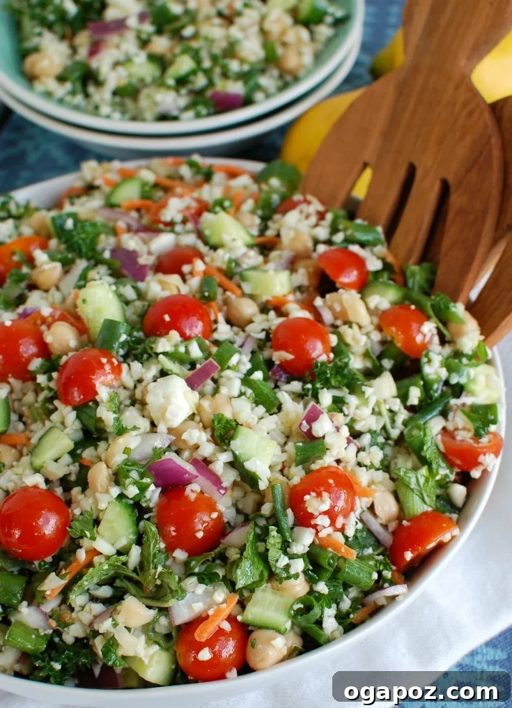 Mediterranean Chickpea Cauliflower Salad being served with salad tongs, ready to be enjoyed.