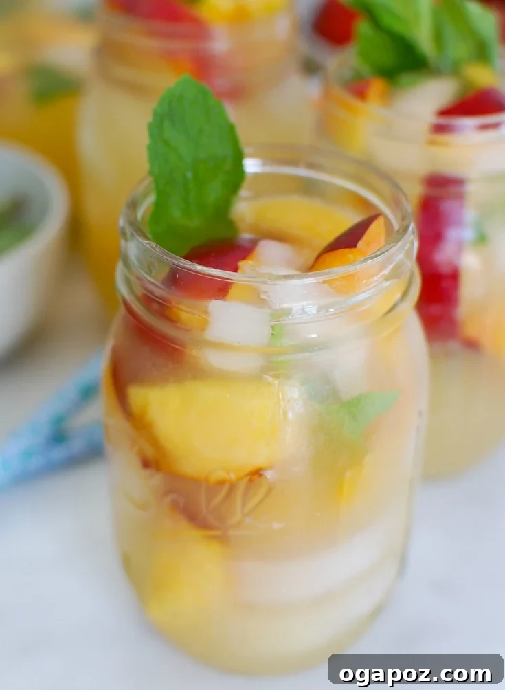 Peachy Fizz Lemonade 2 Refreshing Sparkling Peach Lemonade in a Mason Jar with Fresh Mint and Peach Slices, perfect for summer parties.