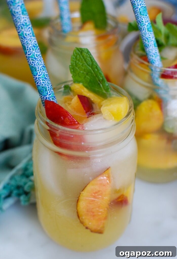 Peachy Fizz Lemonade 5 Close-up of Sparkling Peach Lemonade in a glass, showing peach slices and mint.