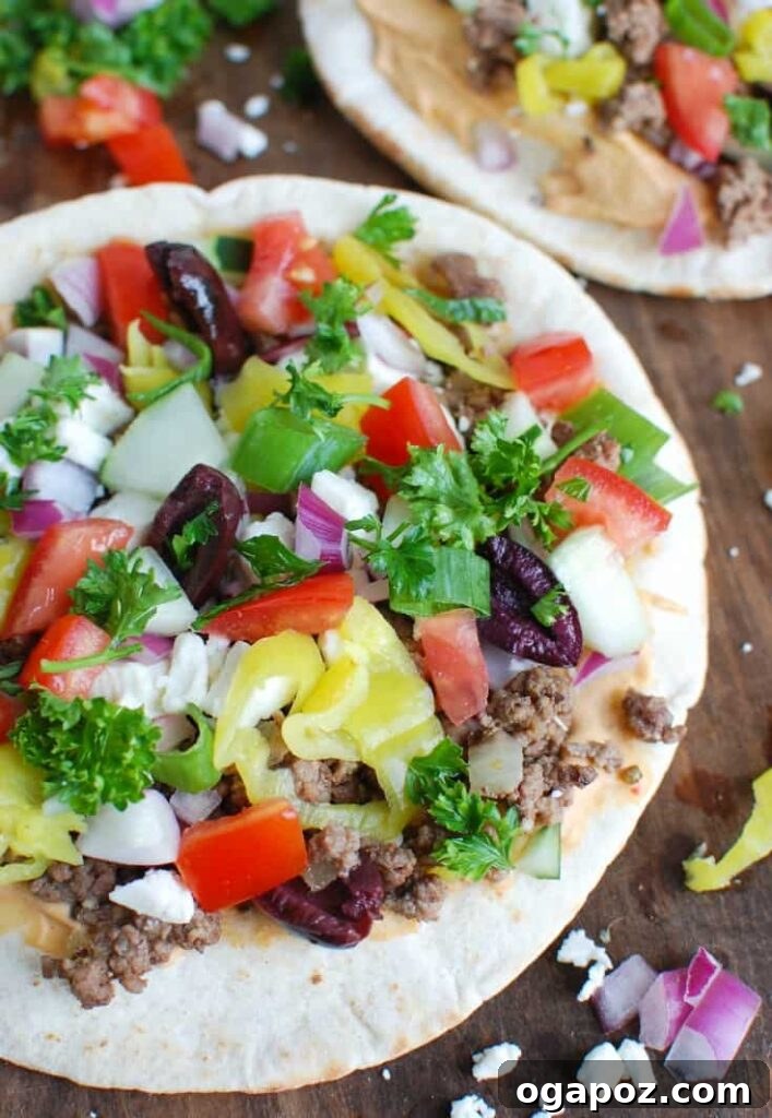 Greek-Style Beef Pita Pizza 2 Close-up of a delicious Greek Beef Pita Pizza, showcasing fresh ingredients like ground beef, feta, tomatoes, and olives on a crispy pita base.