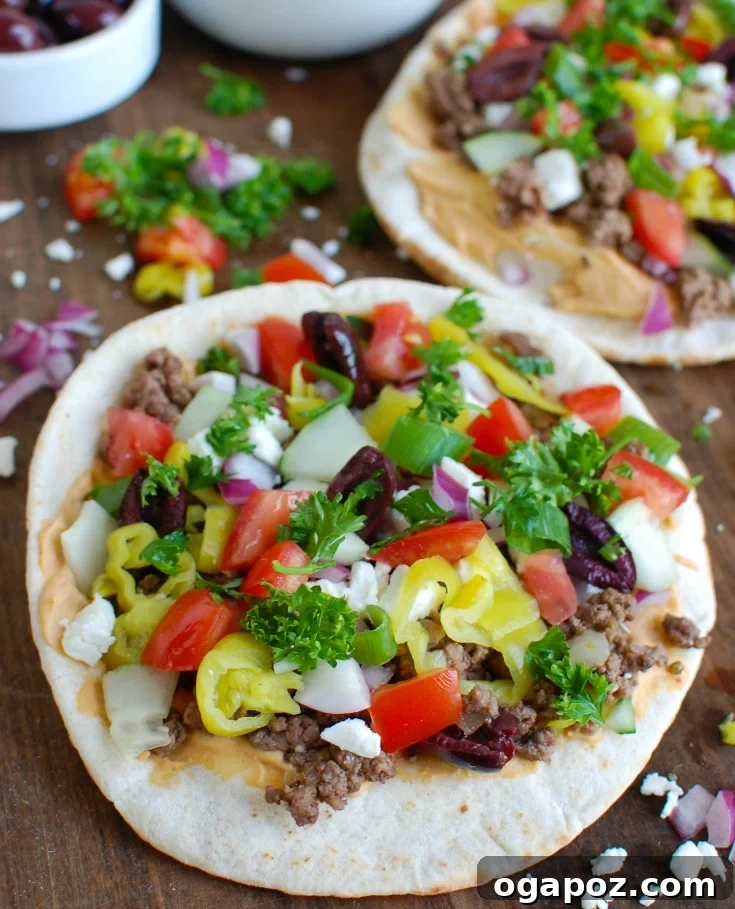 Greek-Style Beef Pita Pizza 3 Two freshly baked Greek Beef Pita Pizzas on a wooden cutting board, garnished with fresh parsley.