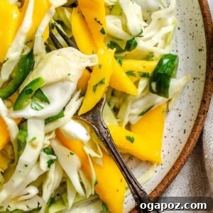 Easy Mango Cabbage Coleslaw in a white bowl with serving spoon.