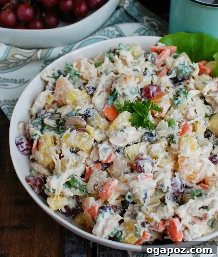 Island Breeze Chicken Salad 2 A beautifully presented Tropical Chicken Salad in a white bowl, garnished with fresh herbs and a vibrant mix of fruits and chicken.