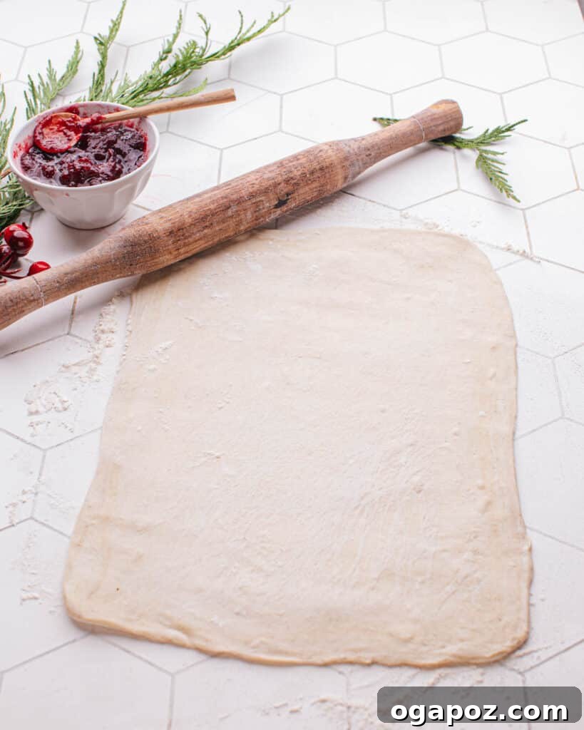 Effortless Brie Everyone Will Love 6 A rolling pin flattening puff pastry dough on a floured surface.