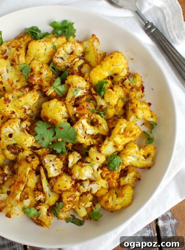 Golden Turmeric Roasted Cauliflower 2 Crispy Turmeric Roasted Cauliflower served fresh from the oven, showcasing its golden hue and slightly charred edges.