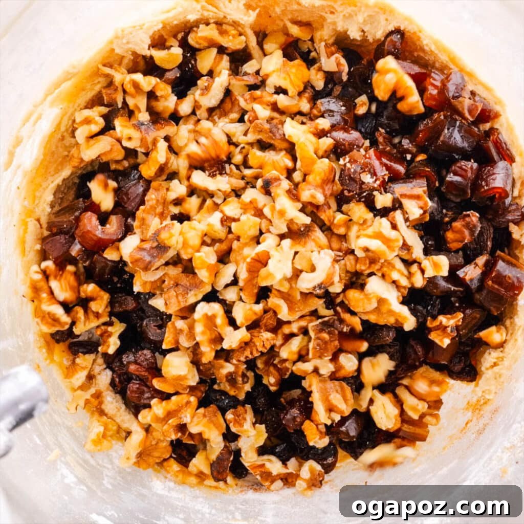 Grandma's Simple Hermit Cookies 3 Dried fruits and nuts being carefully added to a bowl of hermit cookie dough, ready for mixing.