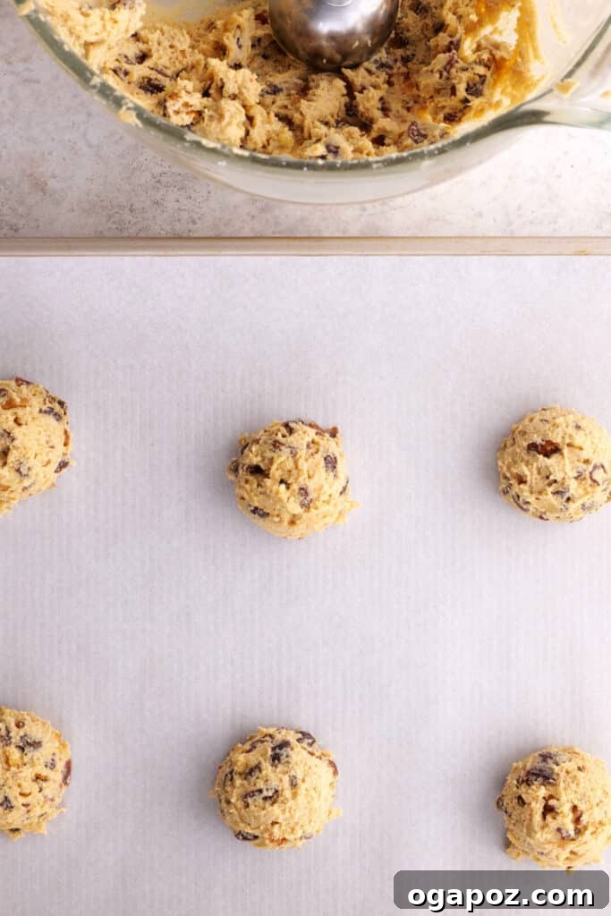 Grandma's Simple Hermit Cookies 8 Scooped hermit cookie dough balls on a baking sheet lined with parchment paper, ready for the oven.
