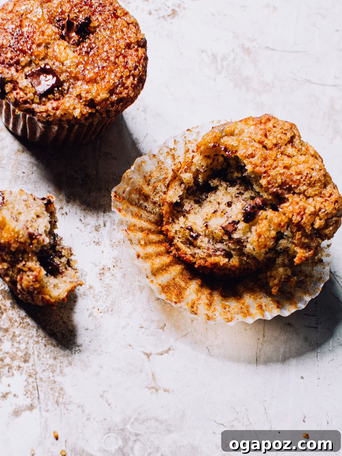 Wholesome Banana Bran Delights 2 Four perfectly baked banana bran muffins with visible chocolate chips, artfully arranged on a cooling rack, highlighting their golden-brown tops and moist texture. The background is softly blurred to keep focus on the delicious muffins.