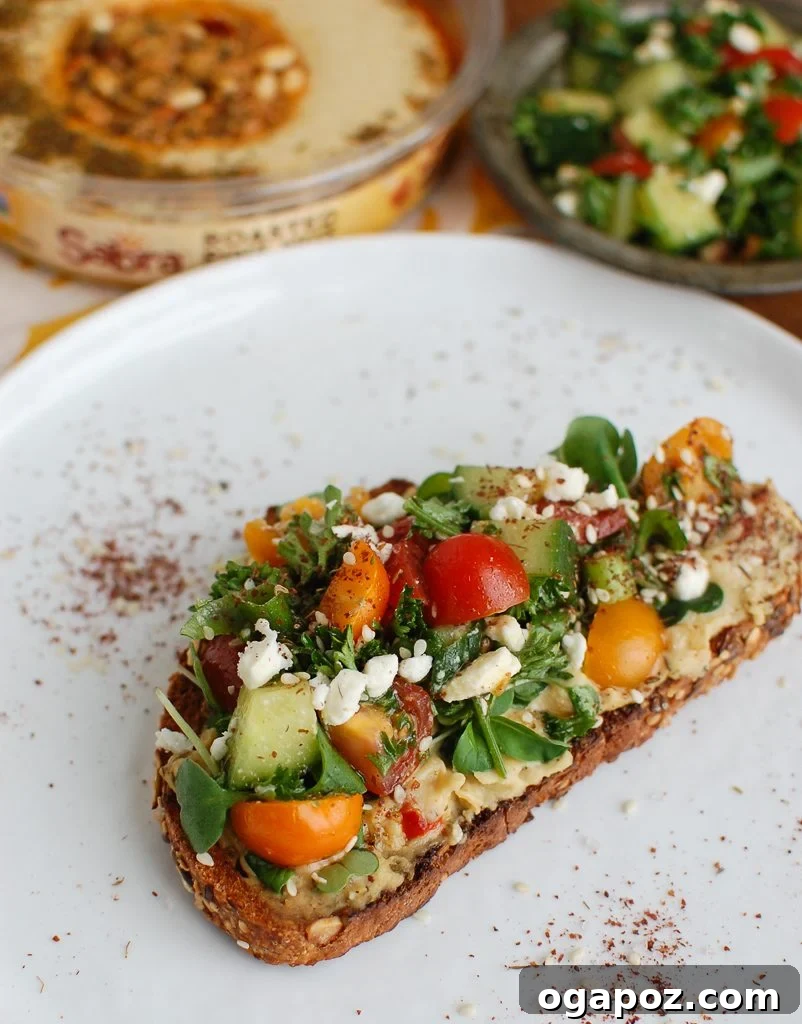 Hummus Toast with Fresh Vegetables A close-up of Mediterranean Hummus Toast with Za'atar, highlighting the fresh vegetables and spice.