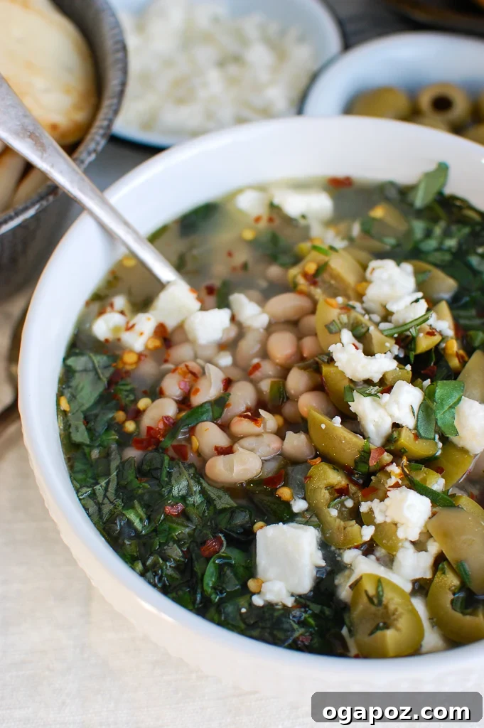 Rustic Mediterranean White Bean Soup 4 A spoonful of Mediterranean White Bean Soup with visible beans, kale, and feta.