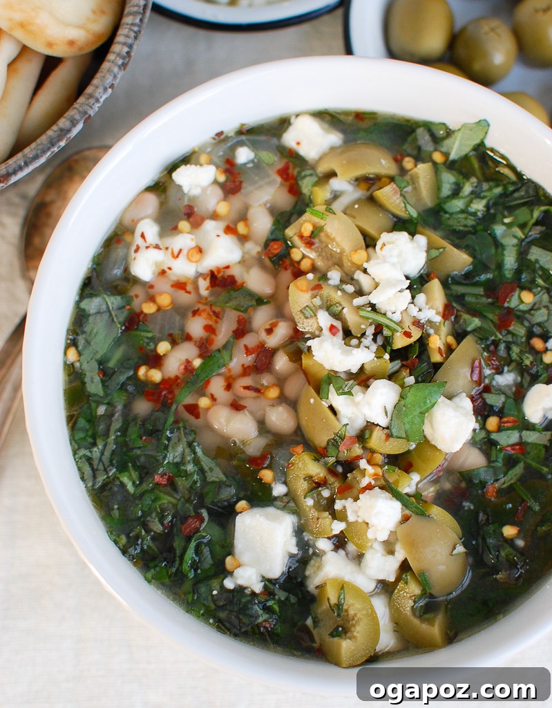 Rustic Mediterranean White Bean Soup 6 A beautiful white bowl of Mediterranean White Bean Soup, garnished with fresh herbs and feta.