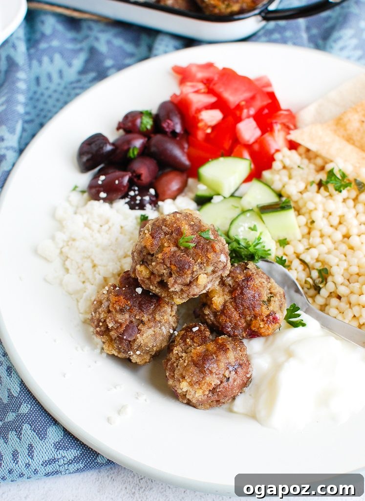 Authentic Greek Keftedes 2 Greek Meatballs served on a white plate with fresh herbs and a lemon wedge, ready to eat.