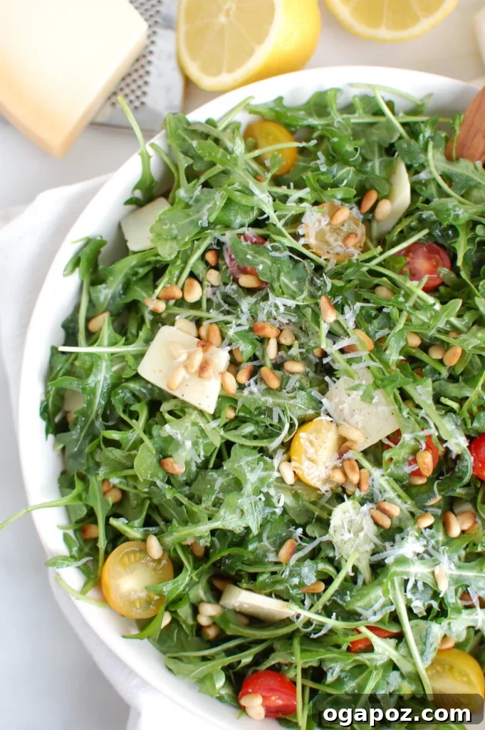 Overhead shot of Lemon Arugula Salad with Pine Nuts in a white bowl, ready to eat.