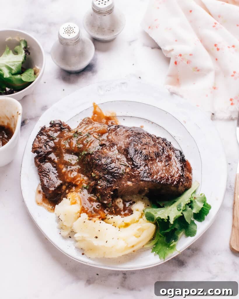 Instant Pot Steak: Fork-Tender Perfection with Savory Pan Sauce 2 Instant pot steak on a plate with mashed potatoes, garnished with herbs.