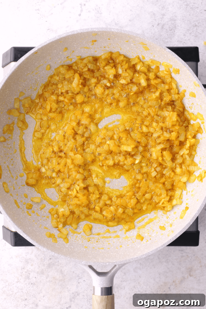 Cooking the finely chopped onions in ghee until they are beautifully golden and caramelized for the Samosa Pie filling