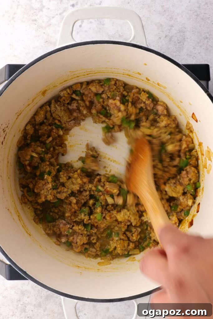 Stirring ground chicken or turkey until thoroughly cooked and mixed with spices for the Samosa Pie filling