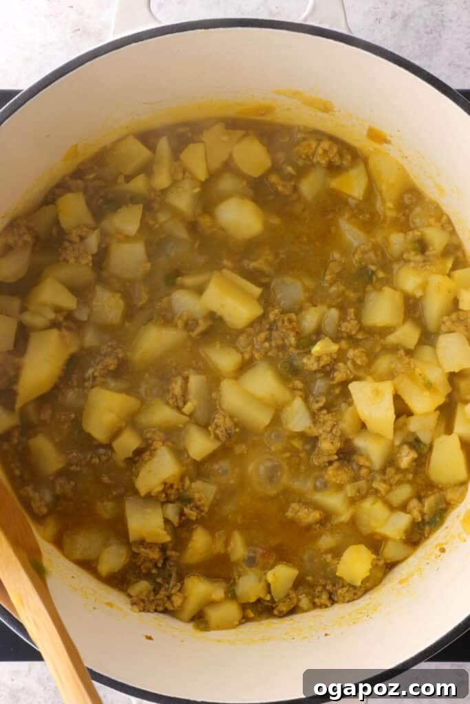 The savory filling cooking in a pan, with diced potatoes and meat absorbing all the rich spices