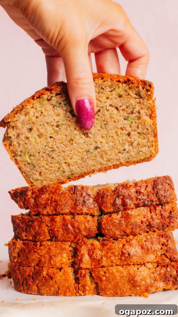 Zucchini Bread That Stays Soft and Moist 2 A pile of sliced zucchini bread with the top slice lifted up, showcasing its moist texture and delicious crumb.