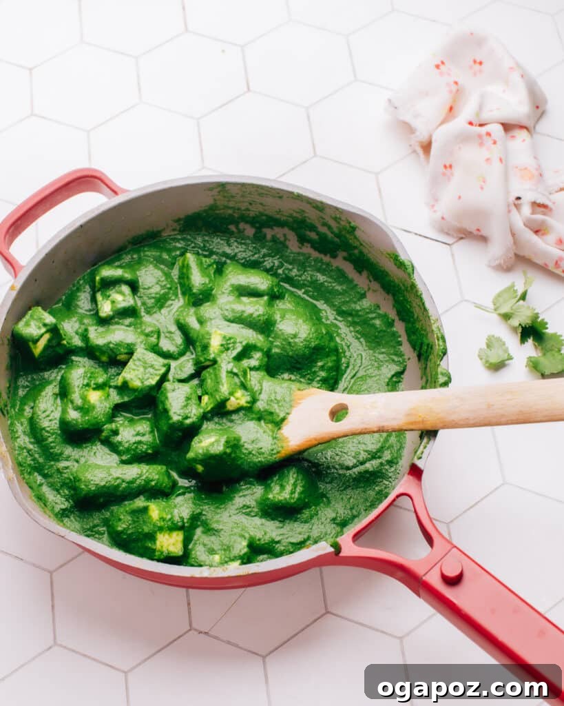 Paneer Perfection: 52+ Recipes for Every Palate 8 Hearty Palak Paneer recipe with tender spinach and paneer cubes, simmering in a pan with a serving spoon, offering ultimate comfort.