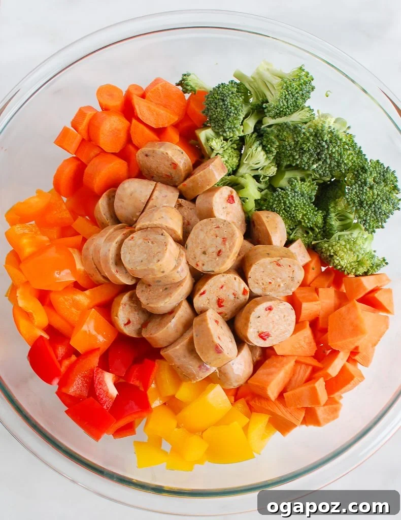 Flavorful One-Pan Chicken Sausage and Roasted Vegetables 5 Arrangement of fresh ingredients for Sheet Pan Chicken Sausage and Vegetables: sliced sausage, sweet potatoes, broccoli, bell pepper, carrots, olive oil, and spices.