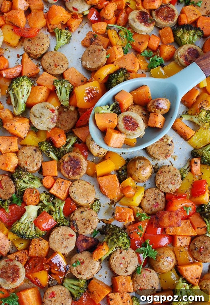 Flavorful One-Pan Chicken Sausage and Roasted Vegetables 7 Sheet Pan Chicken Sausage and Vegetables with a serving spoon, highlighting the texture and color.