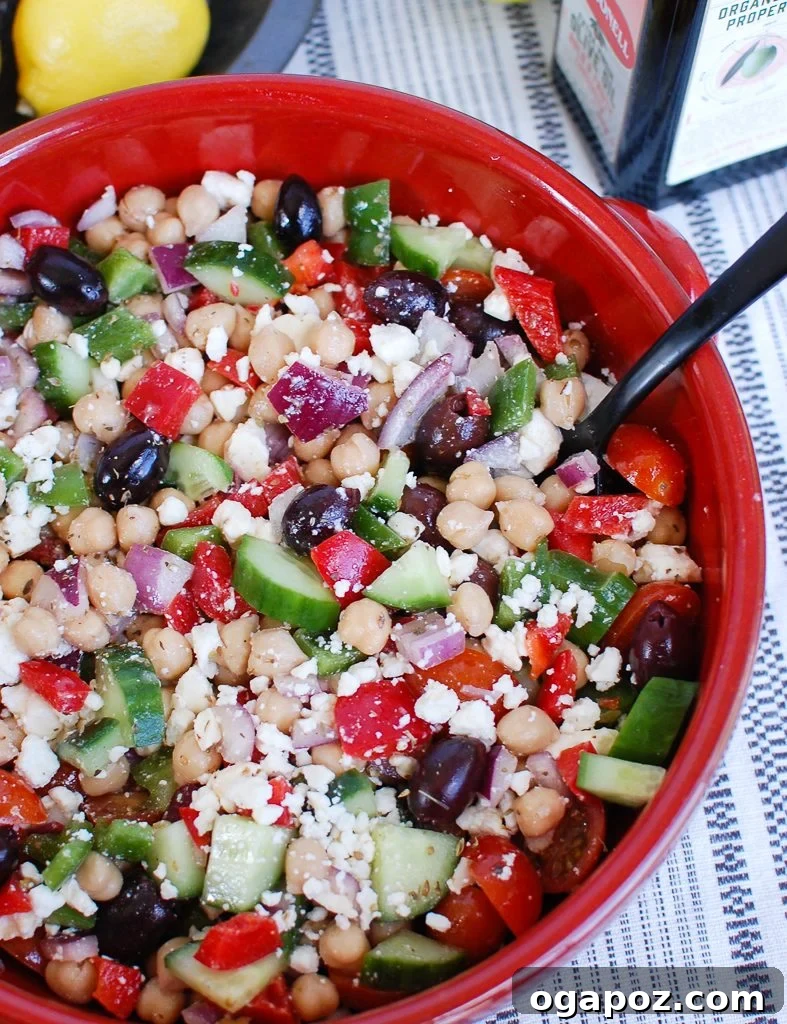 Vibrant Greek Garbanzo Bowl 2 Vibrant Greek Chickpea Salad served in a red bowl, brimming with fresh vegetables and chickpeas.