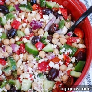 Vibrant Greek Garbanzo Bowl 6 Top-down view of Greek Chickpea Salad in a large serving bowl, garnished with fresh herbs and a drizzle of olive oil.