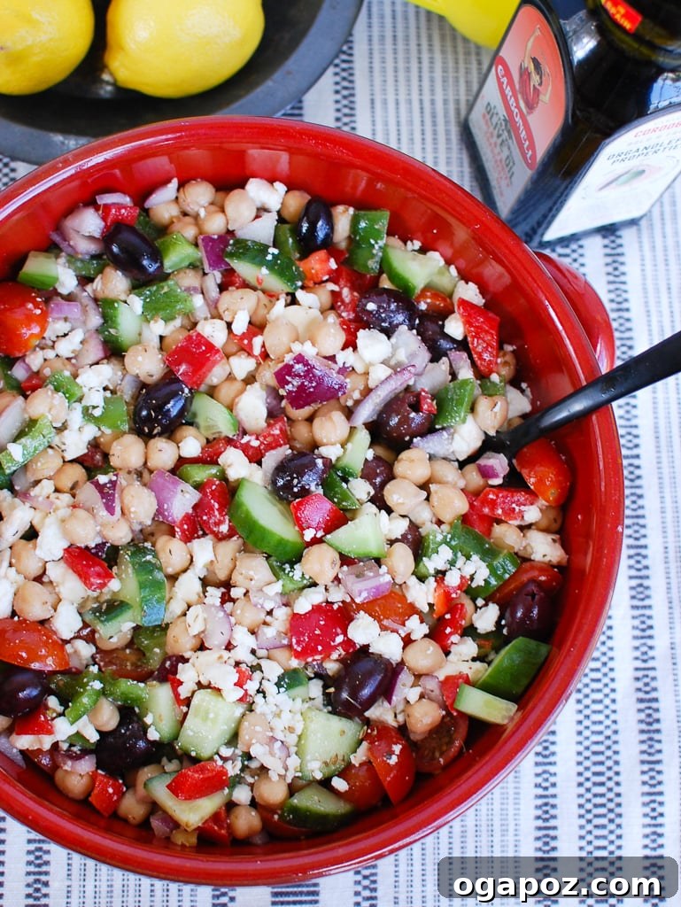 Vibrant Greek Garbanzo Bowl 3 Close-up of Greek Chickpea Salad in a vibrant red bowl, highlighting the crisp vegetables, creamy feta, and plump chickpeas.