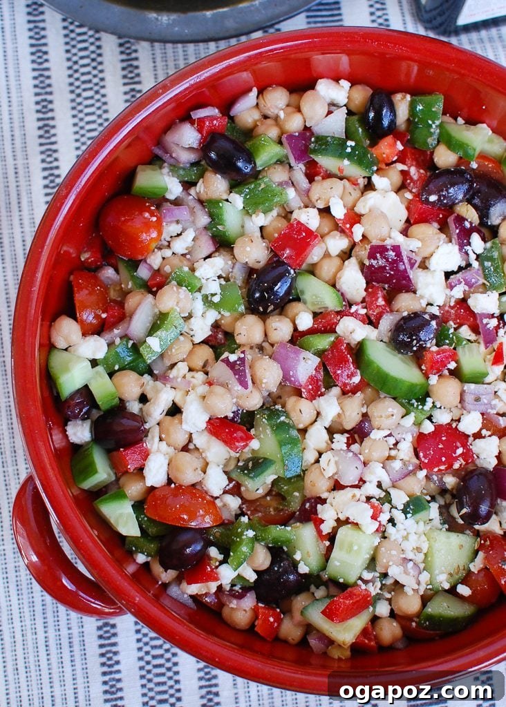 Vibrant Greek Garbanzo Bowl 4 A large serving bowl filled with a colorful and abundant Greek Chickpea Salad, garnished with fresh herbs.