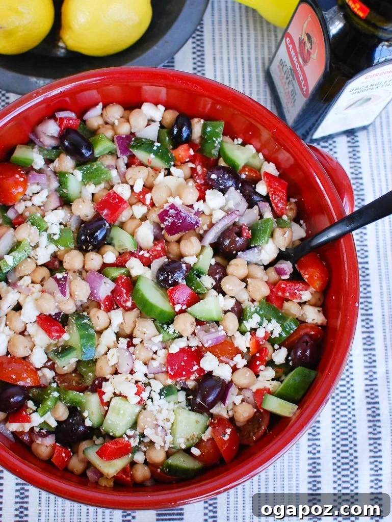 Vibrant Greek Garbanzo Bowl 5 A serving of Greek Chickpea Salad in a bowl with a spoon, ready to be enjoyed as a fresh and healthy meal.
