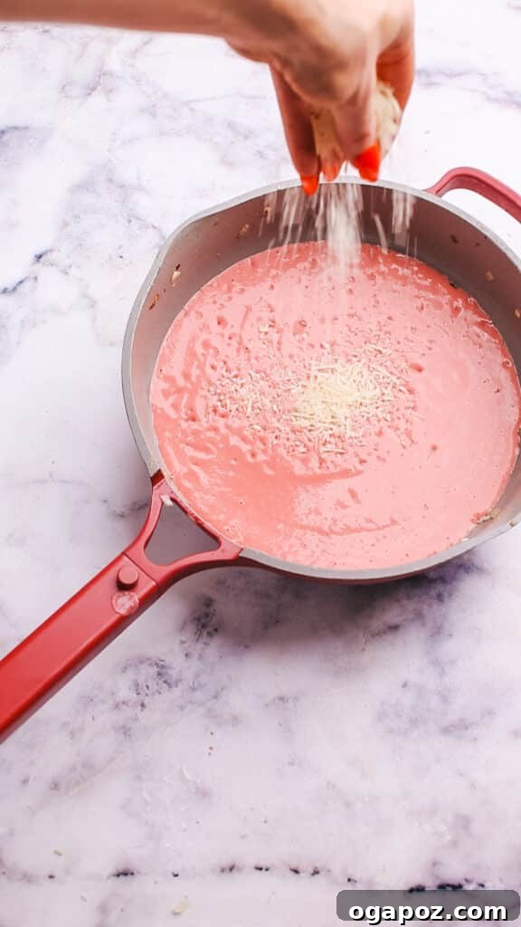 Creamy Beetroot Pasta Delight 11 Adding grated Parmesan cheese to the finished beet pasta sauce.