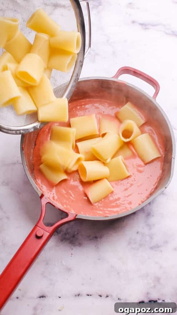 Creamy Beetroot Pasta Delight 7 Tossing freshly cooked pasta with the vibrant beet sauce in a pan.