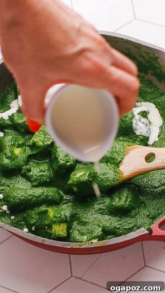 Velvety Palak Paneer 11 A delicate swirl of heavy cream being drizzled over freshly prepared Palak Paneer, enhancing its richness.