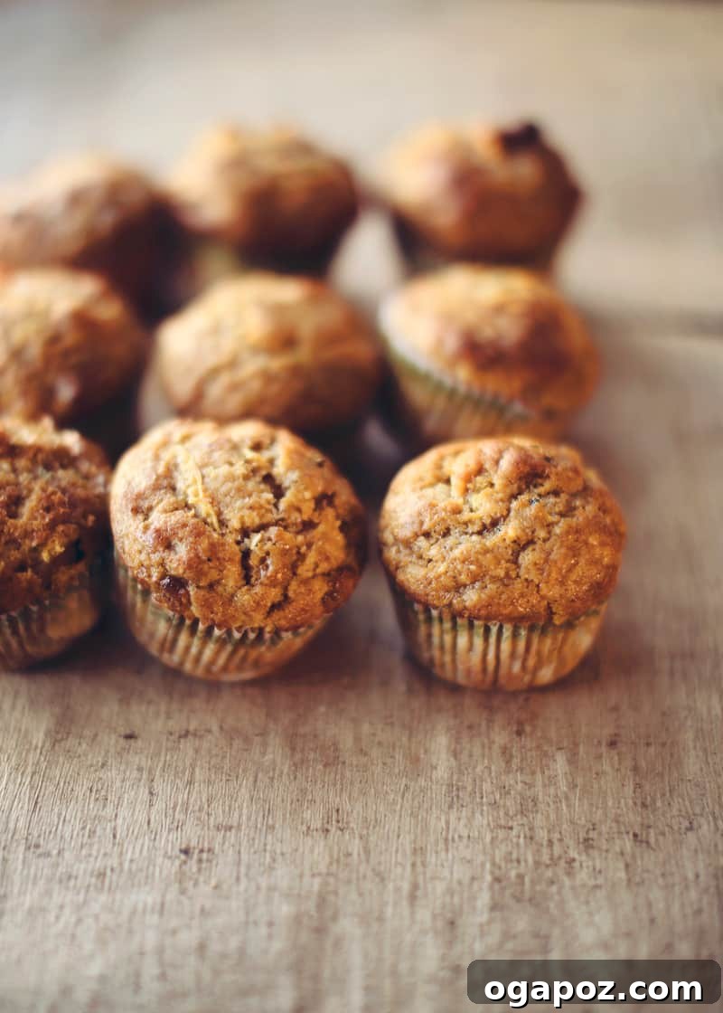 Tender Autumn Pumpkin Zucchini Muffins 2 Pumpkin Zucchini Muffins on a wooden table, perfectly baked and ready to eat.