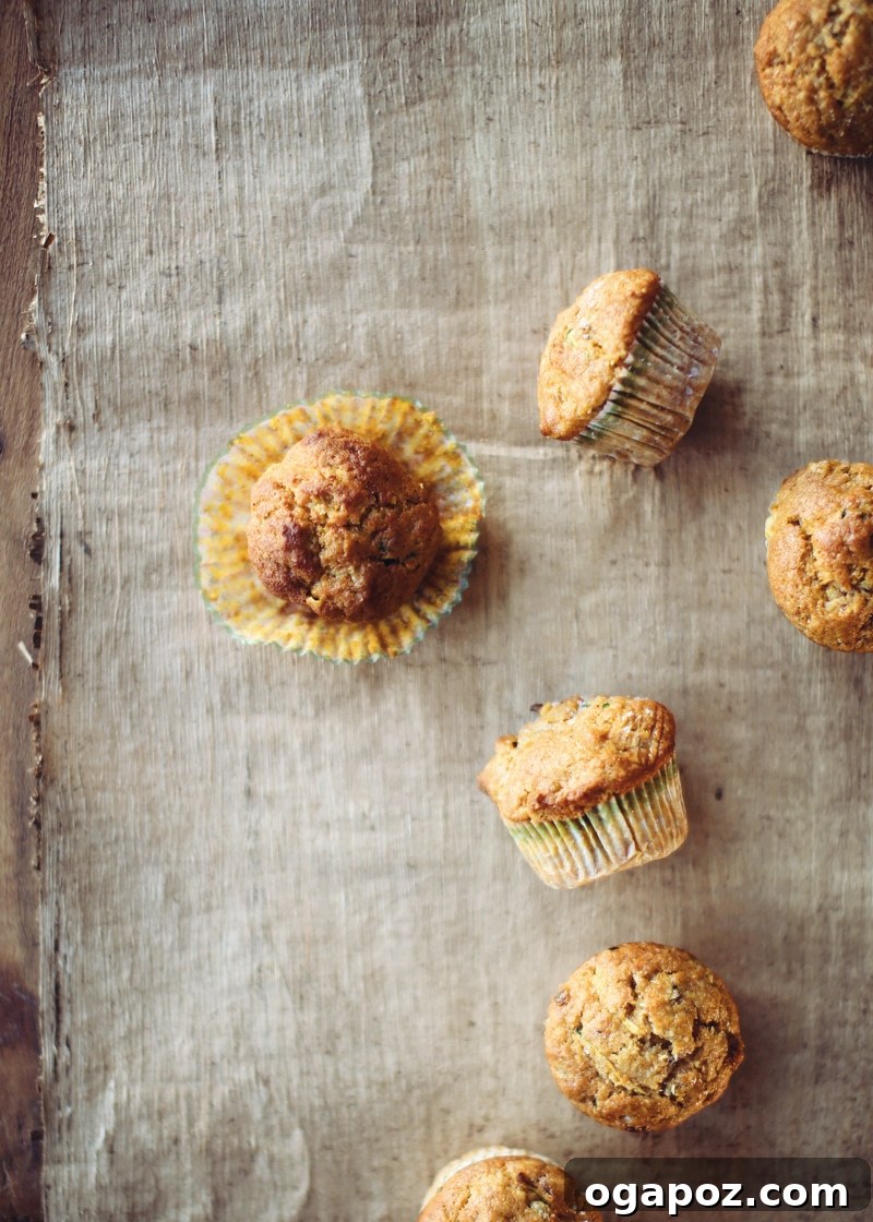Tender Autumn Pumpkin Zucchini Muffins 6 Freshly baked zucchini pumpkin muffins cooling on a wire rack on a countertop.