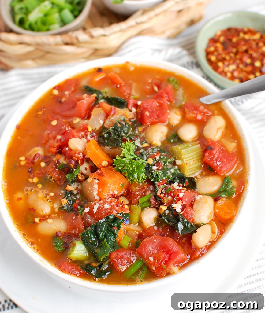 Hearty White Bean and Kale Soup 4 A close-up of a serving of White Bean Soup with Kale, generously garnished with grated Parmesan and a sprinkle of red pepper flakes, ready to be enjoyed.