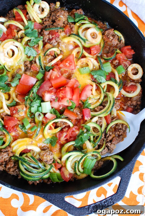 Zesty Mexican Zucchini Medley 6 Mexican Zucchini with a white serving spoon, showing the blend of ground beef, zucchini noodles, and melted cheese.
