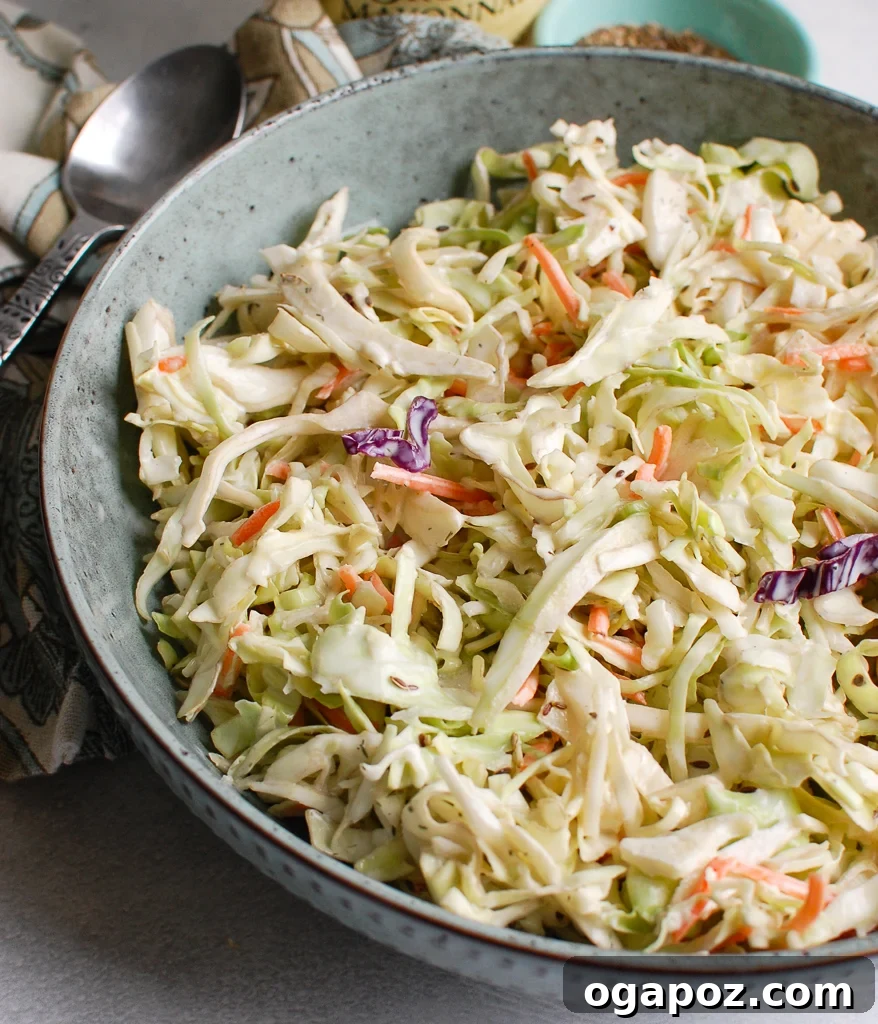 Ultimate Creamy Coleslaw 8 A delicious serving of creamy coleslaw in a blue bowl with a fork, ready to eat.