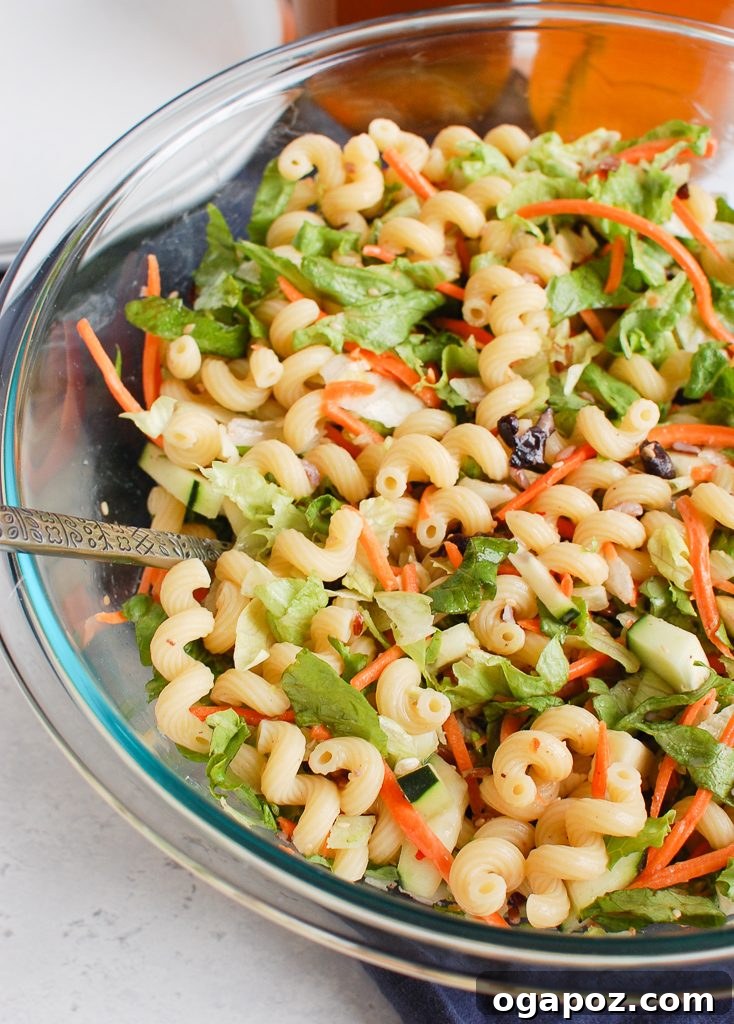Sesame Ginger Pasta Salad 5 Asian Pasta Salad in a white bowl, garnished with fresh cilantro and visible carrots.