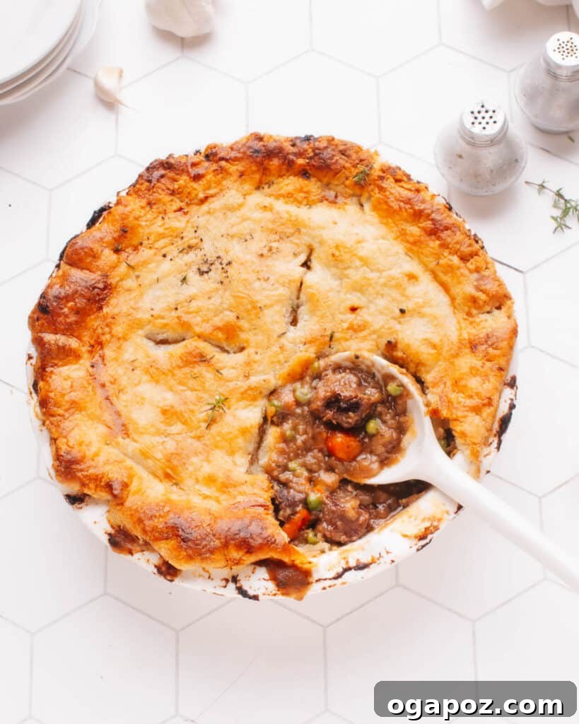 Hearty Winter Casseroles for Ultimate Comfort 19 Hearty Beef pot pie with a spoon serving a portion, revealing tender meat and vegetables