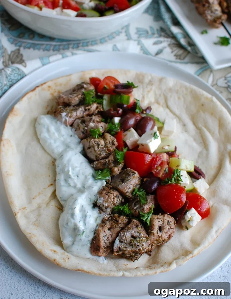 Mediterranean Grilled Pork Skewers with Cooling Tzatziki 4 Pork Souvlaki skewers resting on a warm white pita with tzatziki and Greek salad