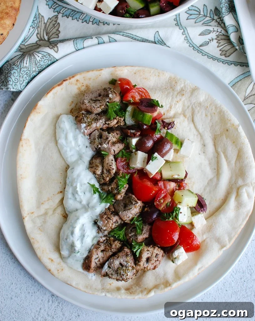 Mediterranean Grilled Pork Skewers with Cooling Tzatziki 5 Pork Souvlaki with Tzatziki, Greek Salad, and pita on a wooden board ready to serve